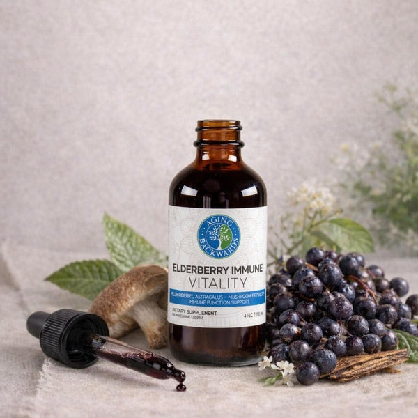 Bottle of Elderberry Immune Vitality supplement with dropper and elderberries on a neutral background